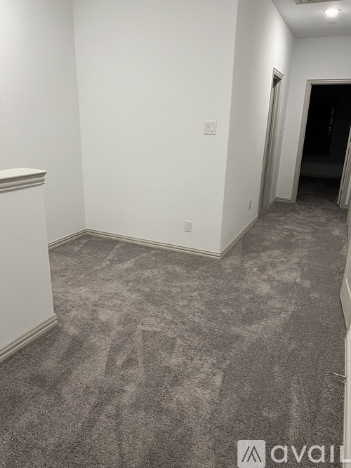 A room with a carpeted floor and a doorway leading to another room.