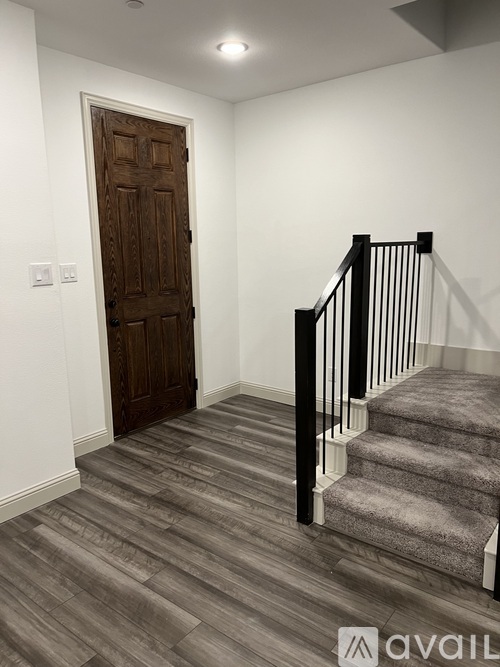 A wooden door is on the left and a staircase with a carpeted runner is on the right.