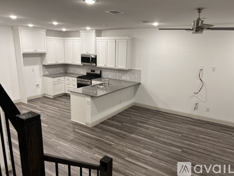 A kitchen with white cabinets and a wooden floor.
