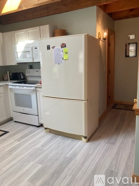 A white refrigerator with a few sticky notes attached to it in a kitchen.