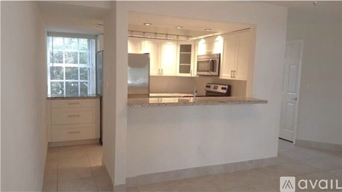 A kitchen with white cabinets and a countertop is available for rent.