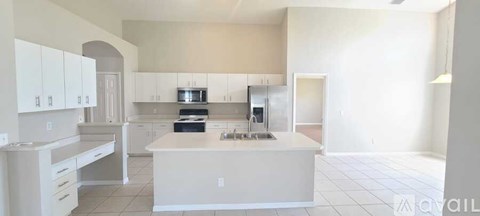 A kitchen with white cabinets and a black counter top.