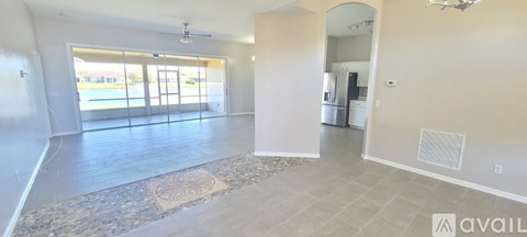 A spacious living room with a rug on the floor and a sliding glass door leading outside.