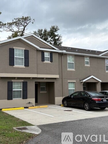 A black car is parked in front of a beige building with a yellow line on the sidewalk.