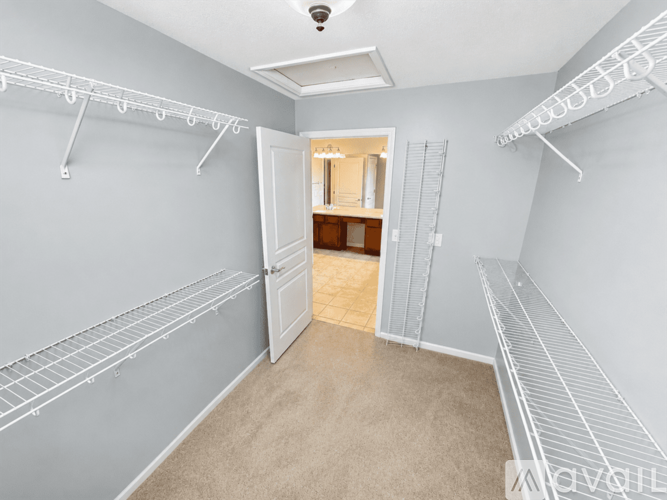 A spacious walk-in closet with white shelving and a carpeted floor.