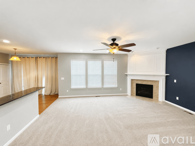 A spacious living room with a fireplace and a ceiling fan.