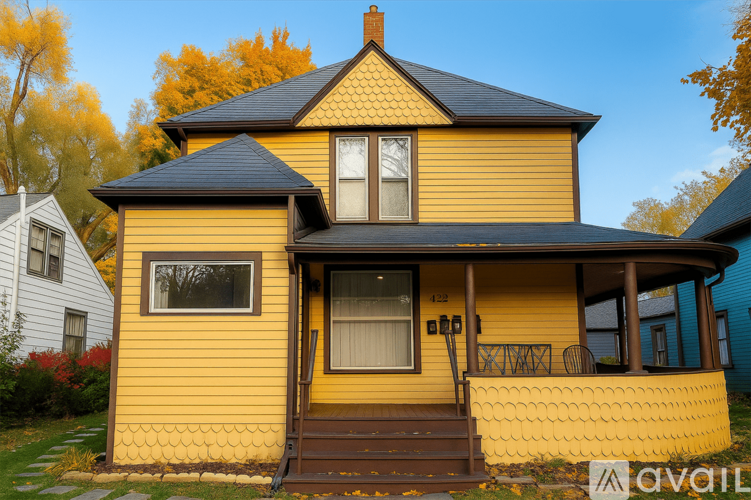 A yellow house with a black roof and a brown door.