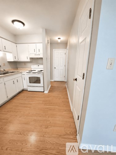 A kitchen with white cabinets and a white stove top oven.