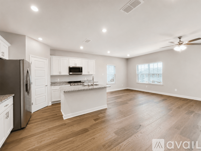 A spacious kitchen with white cabinets and a wooden floor.