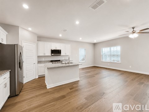 A spacious kitchen with white cabinets and a wooden floor.