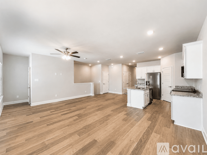 A spacious kitchen with white cabinets and a wooden floor.