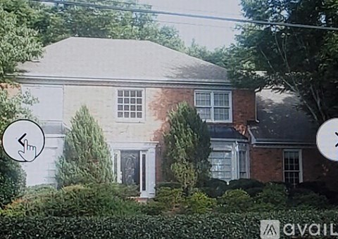 A house with a grey roof and a white door surrounded by greenery.