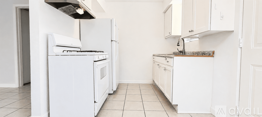 A white kitchen with a refrigerator, oven, and sink.