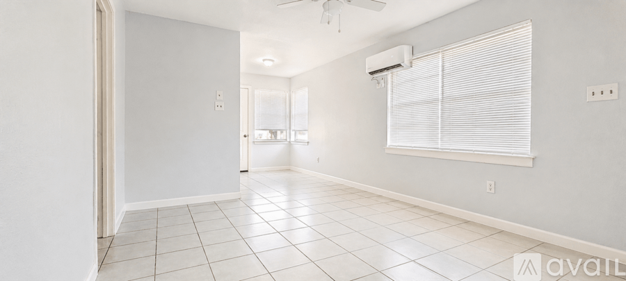 A spacious room with a tiled floor and a window with blinds.