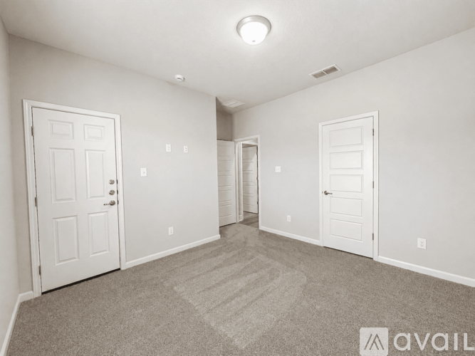 A spacious room with two doors and a carpeted floor.