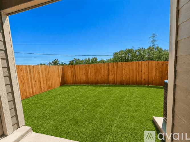 A backyard with a wooden fence and green grass.