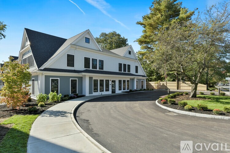 A large white house with a black roof and a driveway in front.