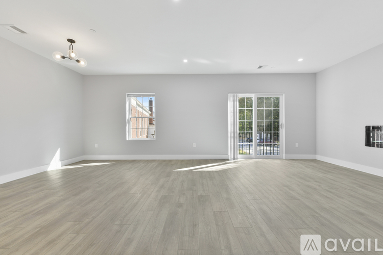 A spacious room with wooden flooring and two windows.