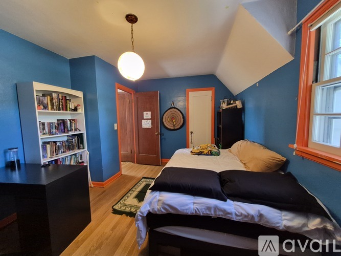 A bedroom with blue walls and a bed with a white comforter.