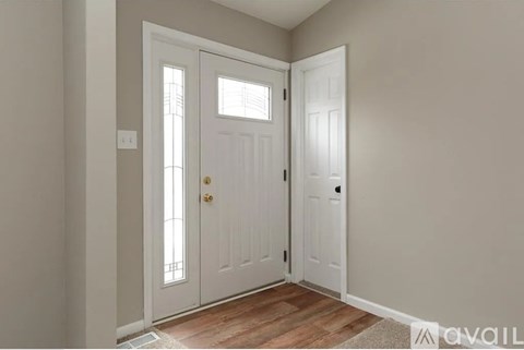 A white door with a glass panel is in a room with wooden flooring.
