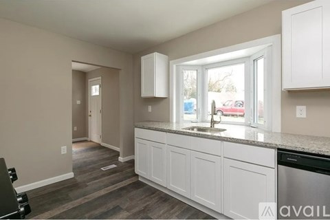 A kitchen with white cabinets and a black dishwasher.