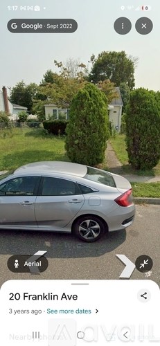 A silver car is parked on the side of a road.