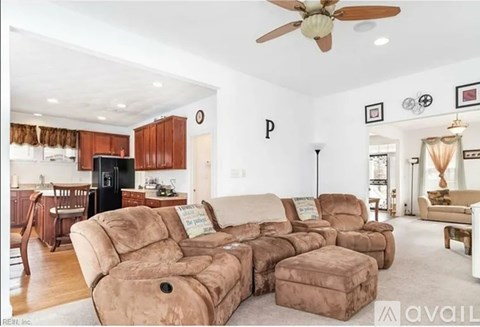 A living room with a brown sofa set and a black refrigerator.
