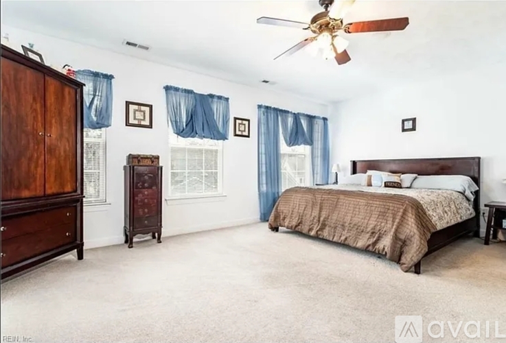 A bedroom with a bed, dresser, and ceiling fan.