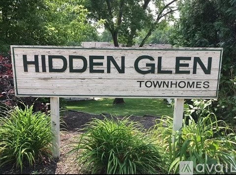 A sign that says Hidden Glen in front of some trees.