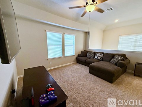 A living room with a brown couch and a ceiling fan.