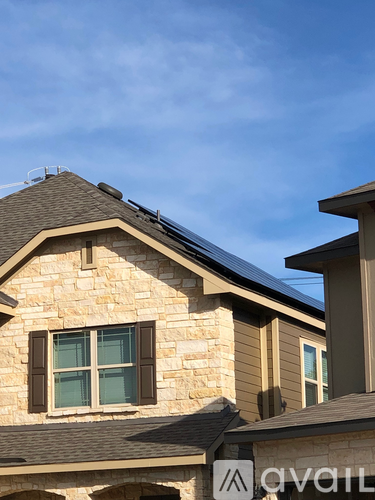 A house with a stone facade and a brown roof with a solar panel on top.