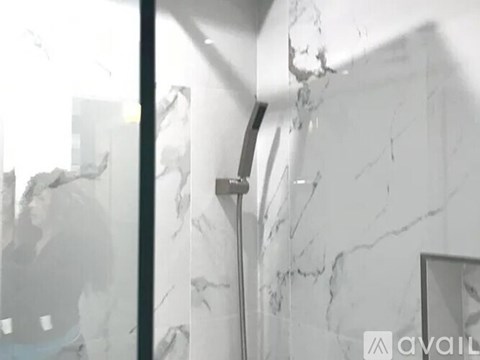 A bathroom with a marble wall and a mirror.
