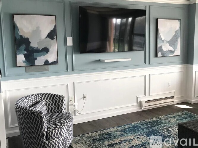 A living room with a chair, a television, and two paintings on the wall.