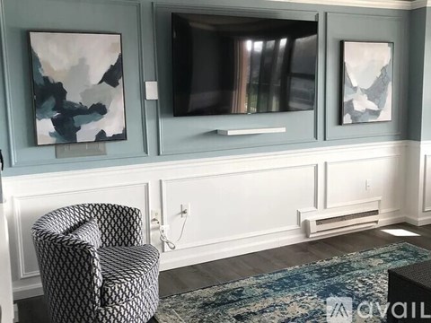 A living room with a chair, a television, and two paintings on the wall.