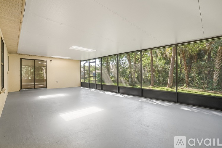 A spacious room with large windows overlooking a forest.