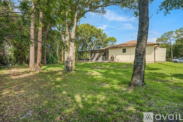 A house is surrounded by trees and grass in the foreground.