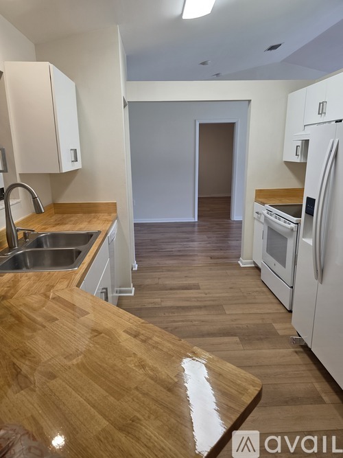 A kitchen with white appliances and wooden countertops.