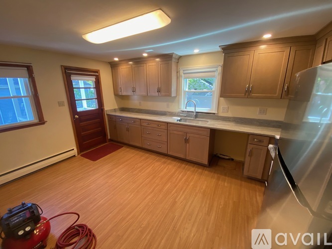 A kitchen with wooden floors and a refrigerator on the right side.