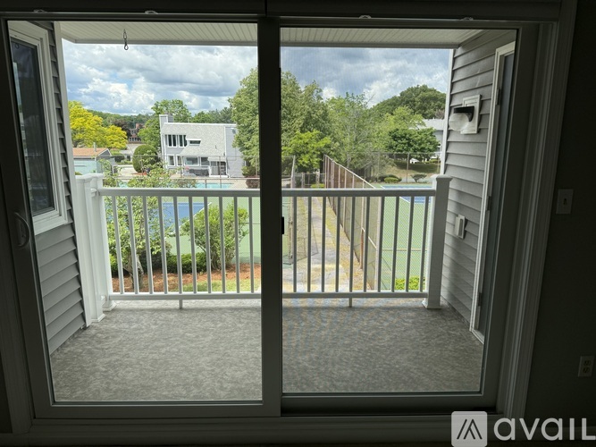 A view from a window looking out to a pool and a house.