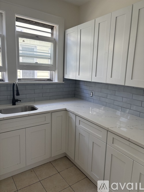 A kitchen with white cabinets and a sink under a window.