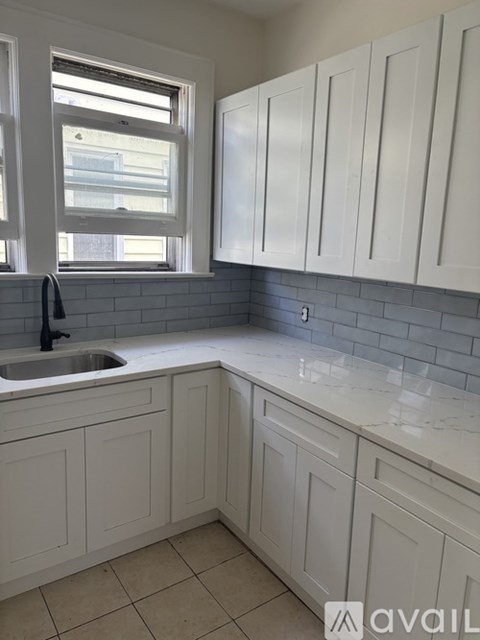 A kitchen with white cabinets and a sink under a window.