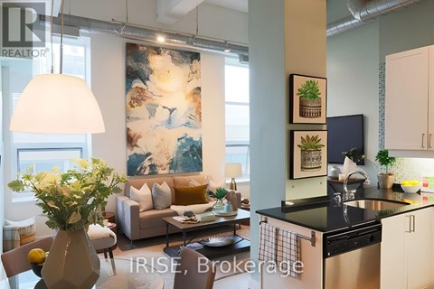 A modern kitchen with a dining table and chairs, a sofa, and a large abstract painting on the wall.