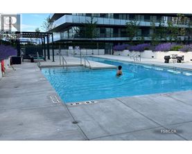 A person is swimming in a pool with a building in the background.