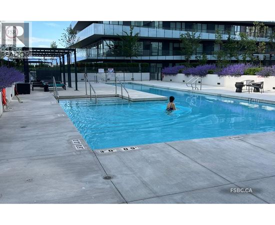 A person is swimming in a pool with a building in the background.