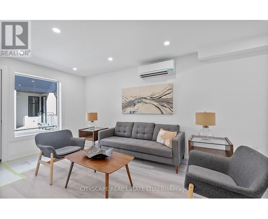 A living room with a grey couch, two armchairs, a coffee table, and a painting on the wall.
