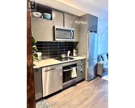 A modern kitchen with stainless steel appliances and a wooden floor.