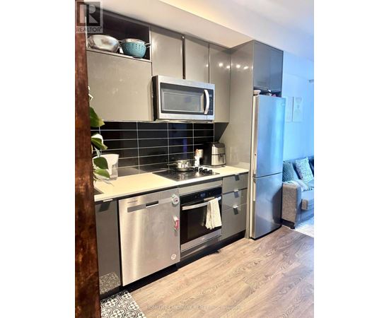 A modern kitchen with stainless steel appliances and a wooden floor.