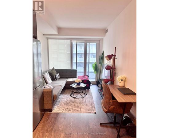 A living room with a couch, a chair, a table, and a window.
