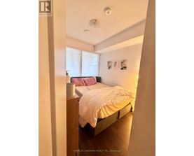 A bedroom with a bed, nightstand, and pictures on the wall.