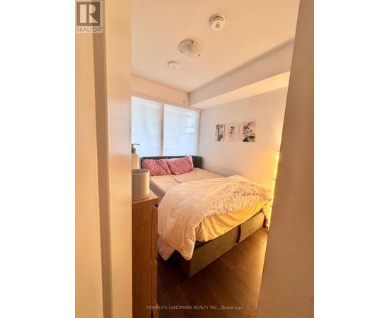 A bedroom with a bed, nightstand, and pictures on the wall.
